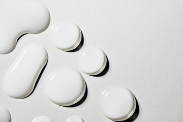 Closeup view of white fluid drops on a textured grey background