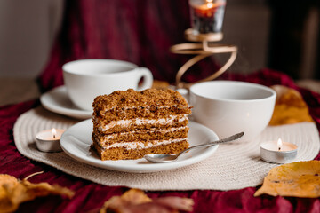 Close-up of a honey cake slice with visible layers and warm tones, styled in a cozy homemade atmosphere.
