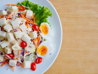A vegetable salad is placed on a plate on the dining table.