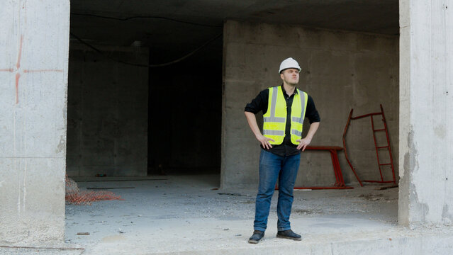 A construction worker inspects the wall of a building on a construction site.