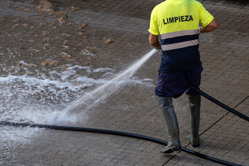 Worker cleaning the street with pressure water