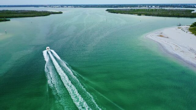 A boat speeds through the vivid teal waters of Stump Pass, its wake splitting the channel between white sand and mangrove shoreline as it heads toward Lemon Bay on Florida&rsquo;s Gulf Coast.