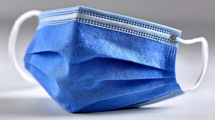 Blue surgical mask on a light surface, symbolizing healthcare.