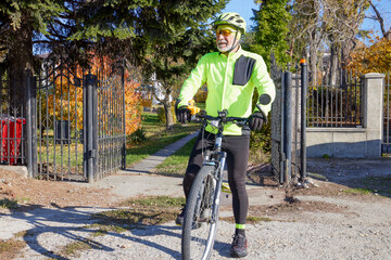 Obraz premium Old man exercising by riding a bicycle on a beautiful autumn day
