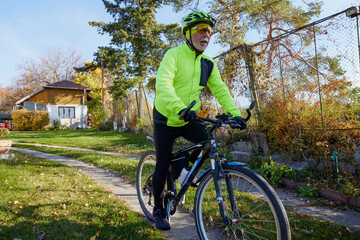 Obraz premium Old man exercising by riding a bicycle on a beautiful autumn day