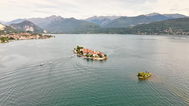 Drone shot pulls back to reveal the full expanse of Isola Bella, showcasing its Palazzo Borromeo and terraced Baroque gardens as it sits within Lake Maggiore, Stresa, Italy, with the Alps background