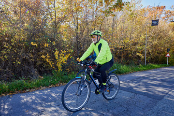 Obraz premium An old man who is passionate about cycling rides his bike with his son, enjoying a beautiful autumn day.
