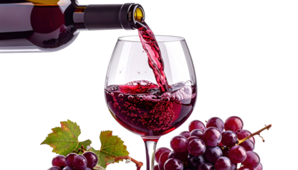 Crimson liquid flows from bottle, filling a glass, accompanied by grapes