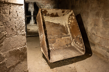 Close-up of an old, heavily rusted mining skip or tilting wagon bucket, abandoned inside the dark...