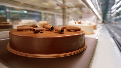Rich chocolate cake displayed in bakery refrigerated showcase