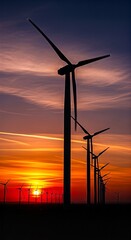 Obraz premium Wind Turbines Silhouetted Against a Vibrant Sunset Sky, Generating Clean Energy.