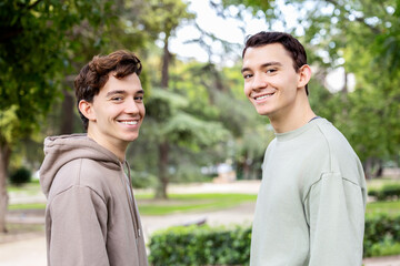 Fototapeta premium Twin brothers smiling at the camera in a green park