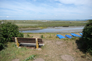 Obraz premium Bench Overlooking Low Tide Creek, Marshland, and Moored Boats