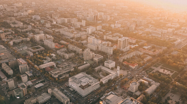 Sunlit aerial panorama of Bishkek, Kyrgyzstan with urban grid, city buildings, parks, and avenues under a warm golden haze.
 - Powered by Adobe