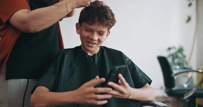 Salon, haircare and child with smartphone, laughing and hair maintenance with dryer and appointment. Happy, boy and funny hairstyles on social media, grooming and watching videos with mobile app