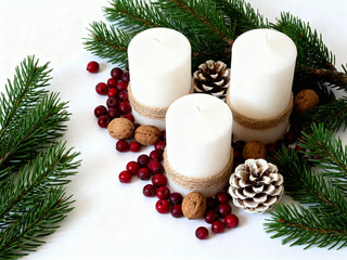 White candles decorated with pine cones and berries for Christmas  