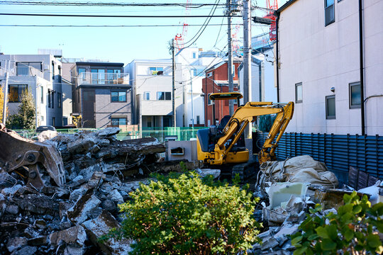 Urban demolition site with a yellow excavator working to tear down a residential building in a suburban Japanese neighborhood on a clear autumn day - Powered by Adobe
