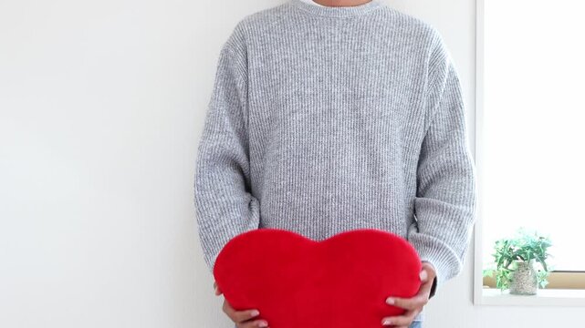 ハートのクッションを投げて受け止める男性（30代、日本人、顔無し）