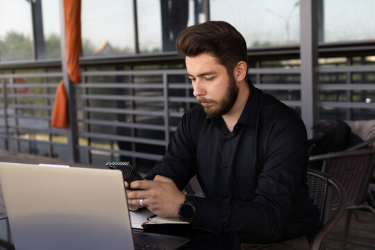 Man is sitting at a table outdoors or in a cafe setting