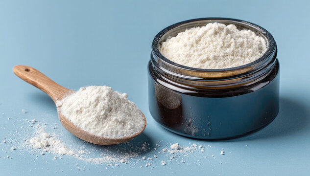 An open glass jar of creatine monohydrate powder and a wooden measuring spoon on a blue background. A sports supplement for training and muscle building.
