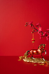 Side vertical view featuring a red backdrop with a gold ox statue, scattered coins and plum blossoms, symbolizing luck and prosperity for Chinese New Year celebration