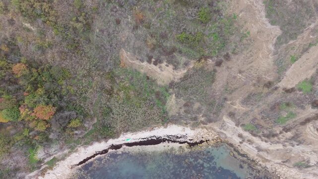 Aerial drone view of dry shrubs and patchy vegetation covering rugged terrain with natural textures forming a wild arid landscape
