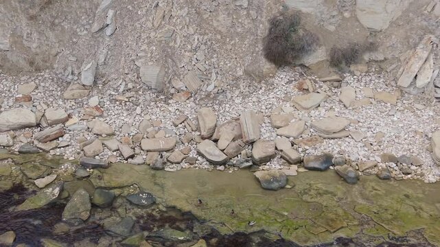 Aerial drone view of rocky slope with loose stones, dry soil and natural textures forming a rugged eroded landscape in daylight
