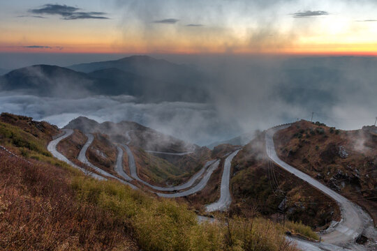 Sunset Over Zuluk Zig Zag Road with Rising Fog and Winding Path. A spectacular high-angle view of the famous Three Level Zig Zag Road at Zuluk