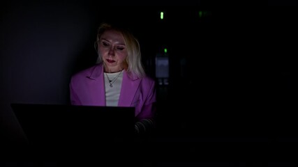 Businesswoman works diligently on her laptop in a dark server room. The screen's glow highlights her concentration, symbolizing late-night work, IT challenges, and dedicated technology professionals. - Powered by Adobe
