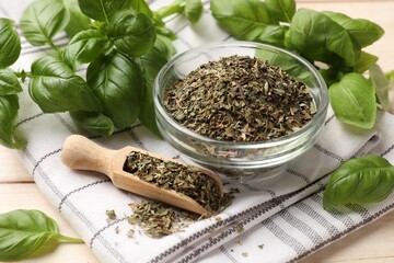 Dry basil leaves, fresh ones, bowl, scoop and napkin on light wooden table, closeup