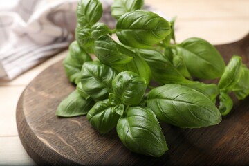 Fresh basil leaves on light wooden table, closeup