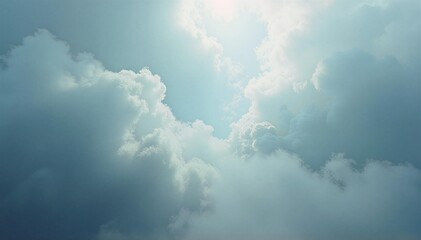 Soft clouds in bright blue sky with sunlight peeking through  