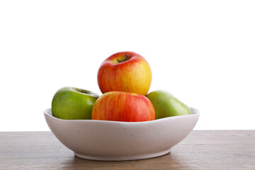 Red and green ripe apples in bowl on wooden table against white background
