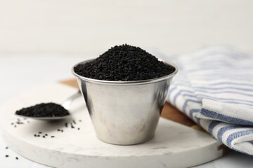 Aromatic black caraway in bowl and spoon on table, closeup