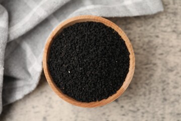 Aromatic black caraway in wooden bowl on grey table, top view