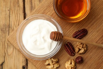 Delicious Greek yogurt with honey and nuts on wooden table, flat lay