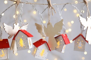 Different Christmas decor hanging on string against grey background with blurred lights, closeup....