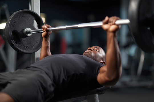 Strong man lifts weights at gym during workout session focusing on strength training and fitness improvement - Powered by Adobe