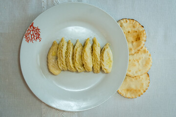 Homemade traditional Sardinian pasta called Culurgiones on a porcelain plate