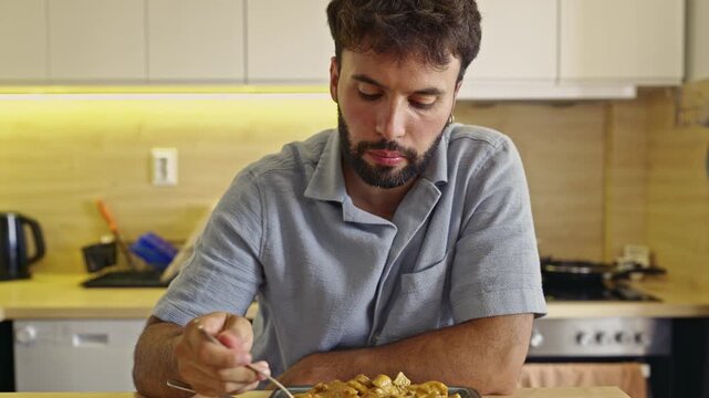 A young man enjoys a delicious and satisfying meal alone in his modern kitchen, complete with clear eating sounds. Perfect for food-related content, vlogs, or realistic daily life scenes.