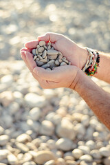 Hands with pebbles and sea pebbles.