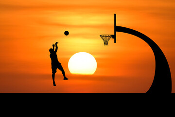 Silhouette of a basketball player making a shot against the backdrop of a setting sun