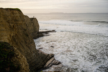 Wide view of fisherman on cliff and breaking surf Peniche Portugal