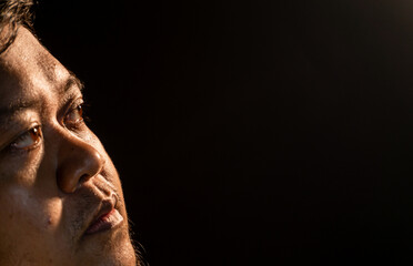 A cinematic portrait angle showing part of a man?s face as he looks upward into warm light, capturing texture and expression. Suitable for hope, reflection, or dramatic storytelling