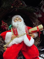 Festive Santa Claus figure nestled in a rustic twig wreath, adorned with pinecones, berries, and a golden rope, holding a scroll—perfect holiday decor evoking warmth, tradition, and Christmas cheer.