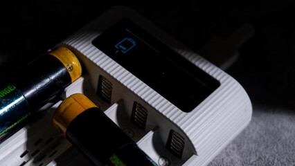 Single active charging slot shown on the charger's display while AA batteries rest nearby. The...