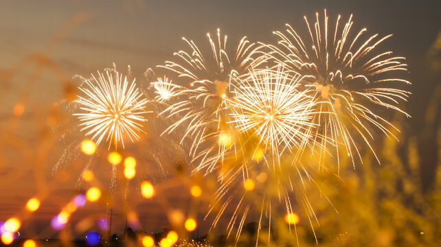 Golden fireworks explode in the night sky over a blurred crowd