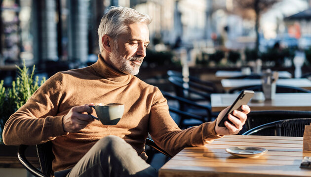 Mature man in turtleneck sweater holding coffee cup and browsing smartphone at outdoor cafe, enjoying sunny day and relaxed atmosphere, smiling with contentment