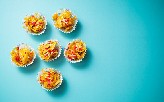 Five cornflake cookies on a turquoise background, captured from a top view. A close-up, selective-focus shot of this popular Malaysian snack, often enjoyed during Eid Mubarak.