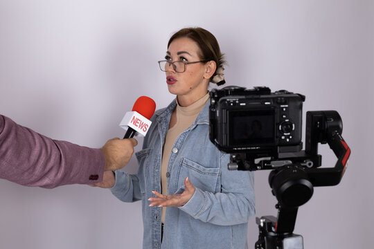 A woman is being interviewed by a reporter with a microphone for a news segment
